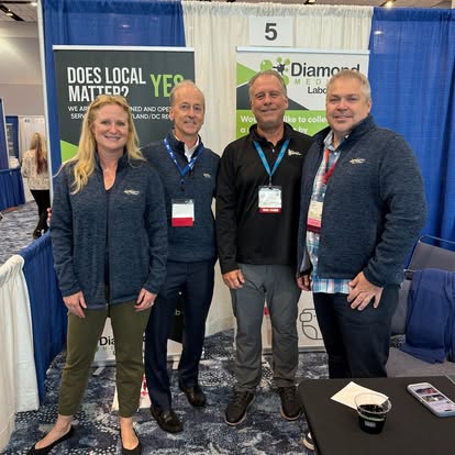 members standing in a booth smiling for the camera